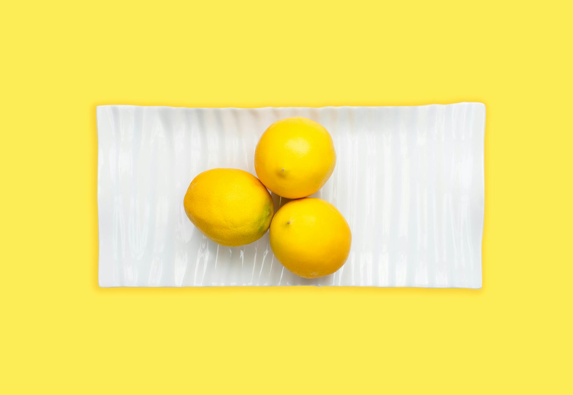 A vibrator surrounded by fresh fruit on a bright yellow background