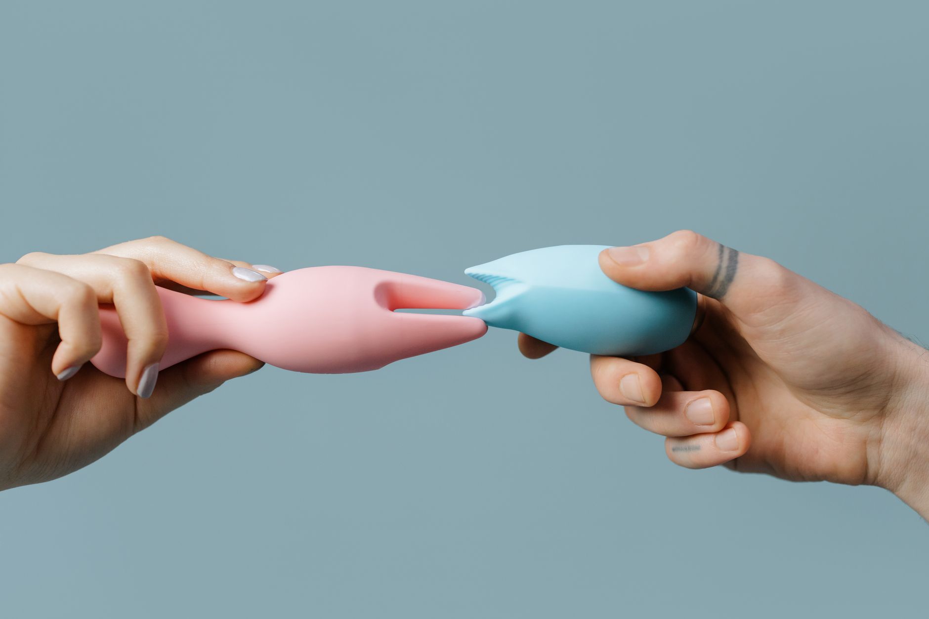 Two hands holding colorful silicone vibrators side by side