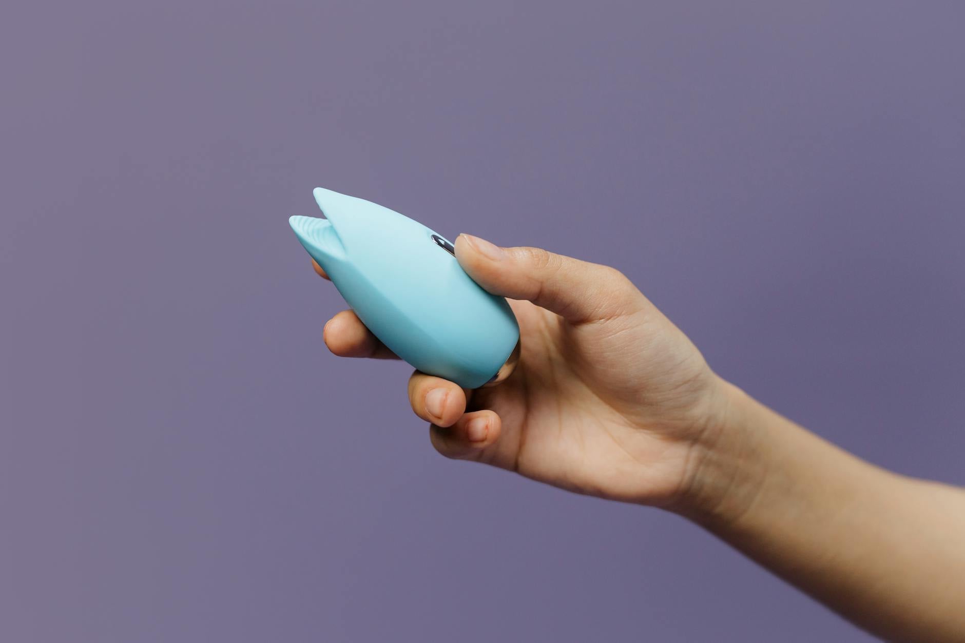 A silicone lemon vibrator held in hand against a purple background, symbolizing self-care and gentle pleasure.